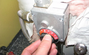A man adjusting the temperature on his water heater thermostat.