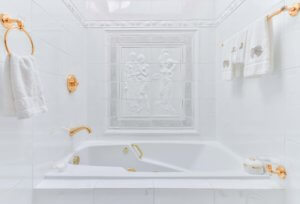 A modern marble style bathtub with a classic roman relief image on the back wall.