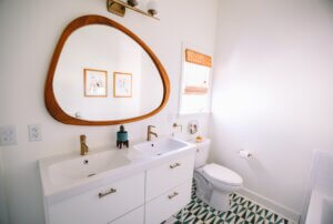 A white bathroom with white appliances and a large circular mirror.